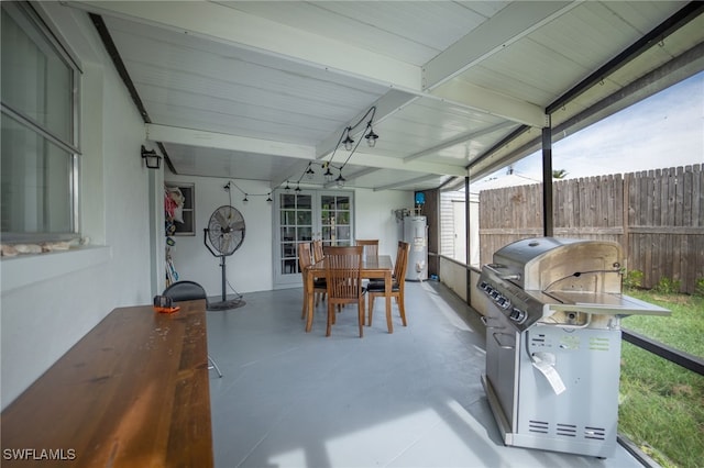 sunroom with vaulted ceiling with beams, gas water heater, and french doors