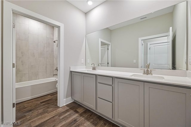 full bathroom with hardwood / wood-style floors, vanity, tiled shower / bath combo, and toilet