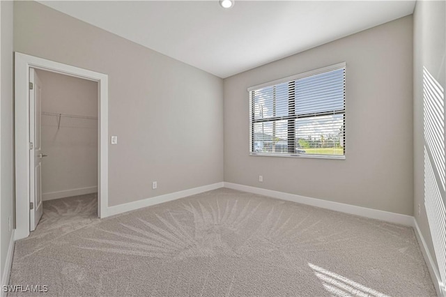 unfurnished bedroom featuring light colored carpet, a spacious closet, and a closet