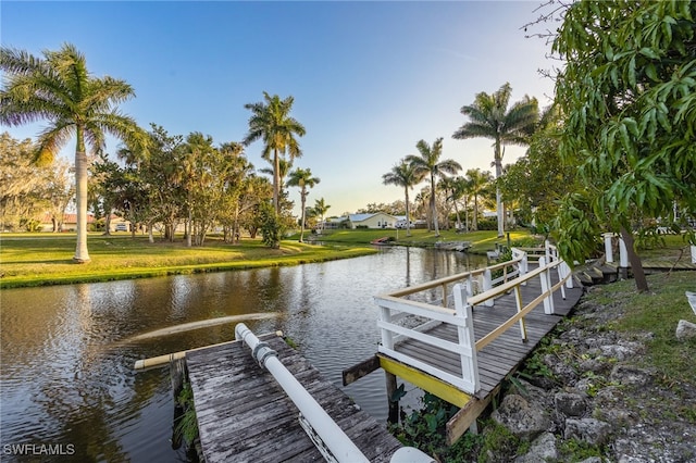 view of dock with a yard and a water view