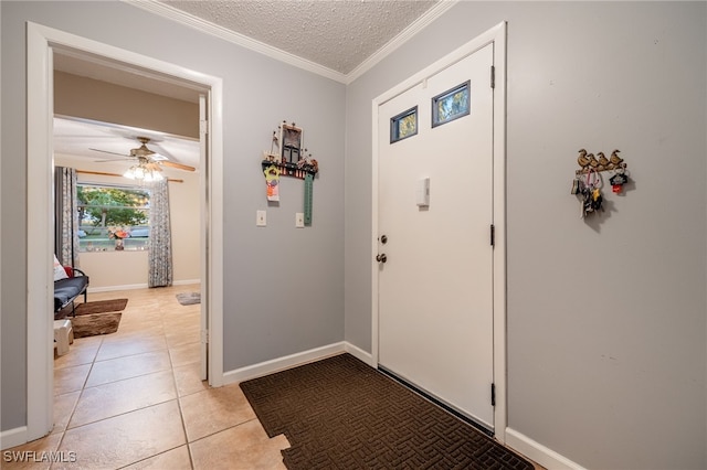 foyer featuring baseboards, light tile patterned flooring, ceiling fan, a textured ceiling, and crown molding