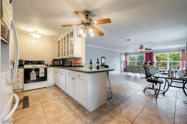 kitchen with dark countertops, white appliances, a peninsula, a breakfast bar area, and ceiling fan