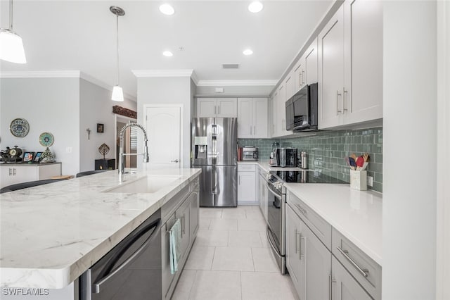 kitchen with a kitchen island with sink, sink, pendant lighting, and appliances with stainless steel finishes