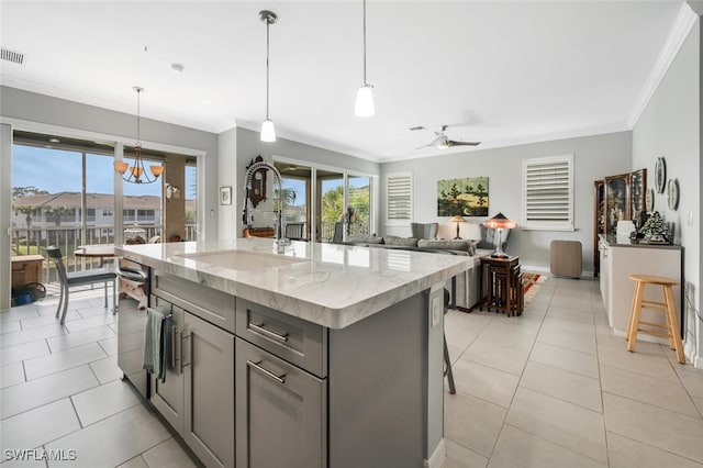 kitchen featuring light stone counters, sink, ceiling fan with notable chandelier, and decorative light fixtures