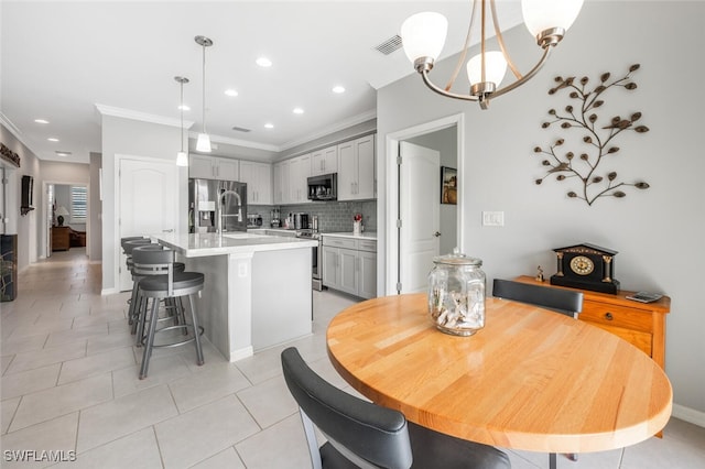 dining space featuring crown molding, light tile patterned floors, and an inviting chandelier