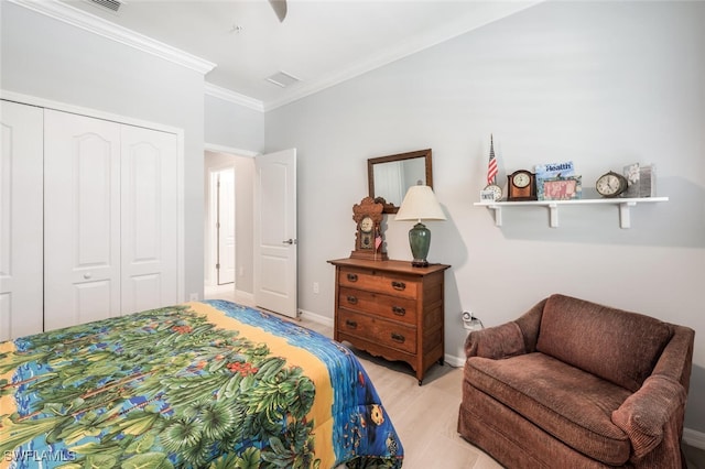 bedroom featuring light hardwood / wood-style floors, crown molding, and a closet