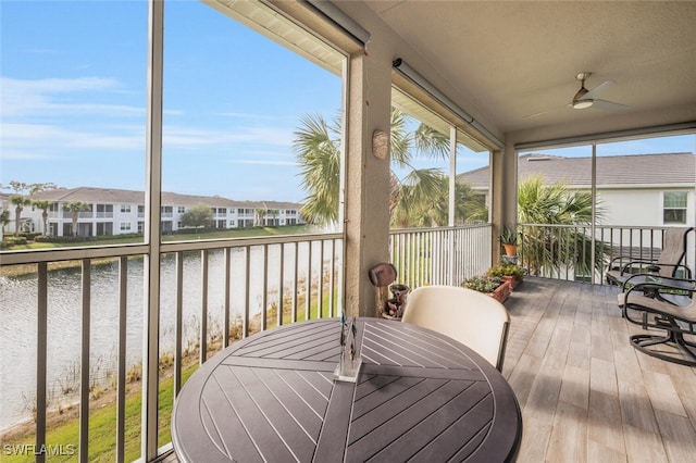 sunroom / solarium featuring ceiling fan and a water view