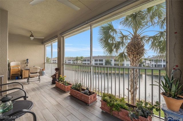 sunroom / solarium with a water view and ceiling fan