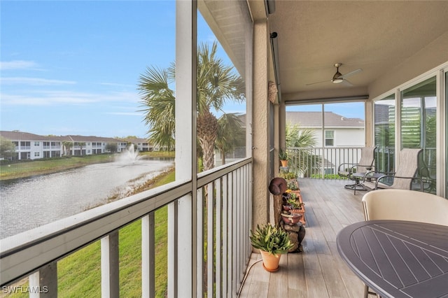 sunroom featuring ceiling fan and a water view