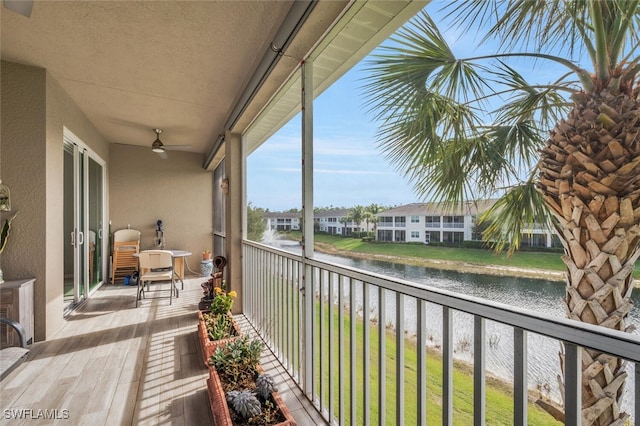 balcony with ceiling fan and a water view