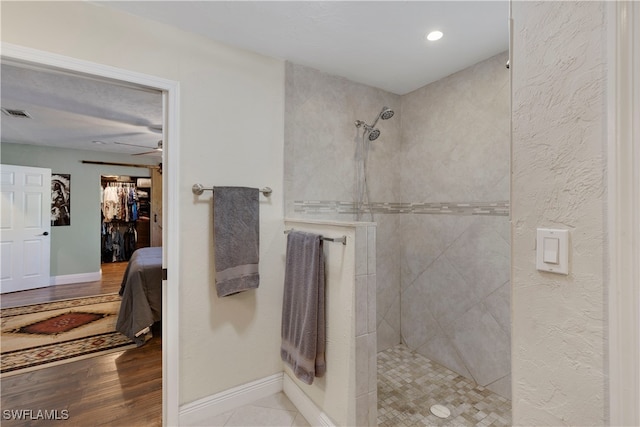 bathroom featuring ceiling fan, hardwood / wood-style flooring, and tiled shower