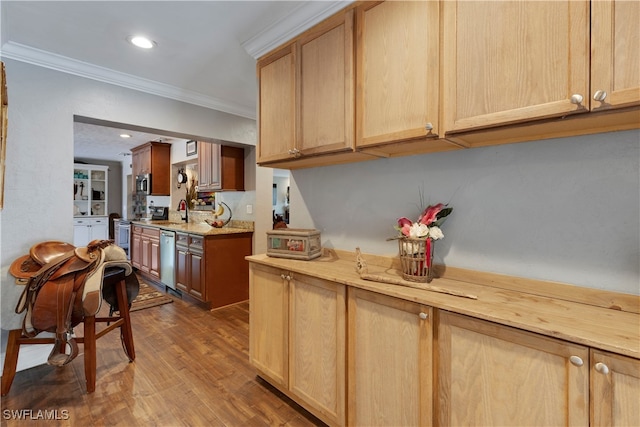 kitchen featuring stainless steel appliances, crown molding, hardwood / wood-style flooring, and sink