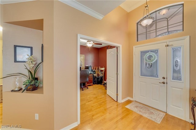 foyer entrance with crown molding, ceiling fan, and wood-type flooring