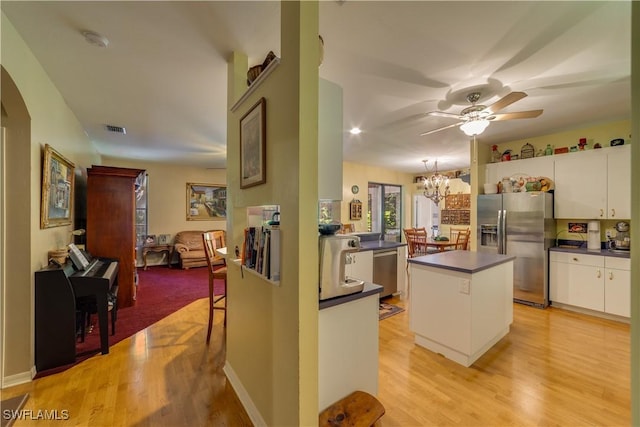 kitchen featuring appliances with stainless steel finishes, ceiling fan with notable chandelier, white cabinets, light hardwood / wood-style floors, and a kitchen island