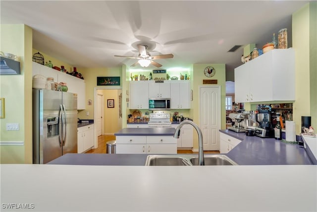 kitchen with white cabinets, appliances with stainless steel finishes, kitchen peninsula, and sink