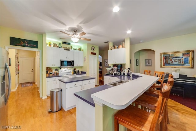 kitchen with white cabinetry, sink, ceiling fan, a breakfast bar area, and appliances with stainless steel finishes