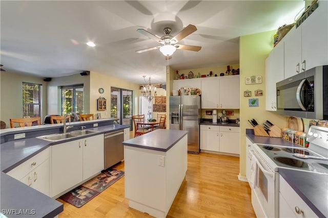 kitchen featuring ceiling fan with notable chandelier, stainless steel appliances, sink, a center island, and white cabinetry