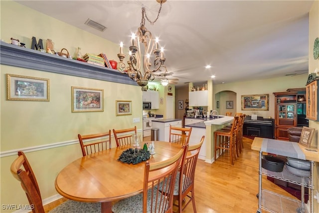 dining space with light hardwood / wood-style floors and ceiling fan with notable chandelier