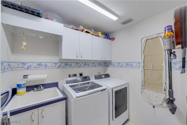 washroom featuring cabinets, washing machine and dryer, and sink