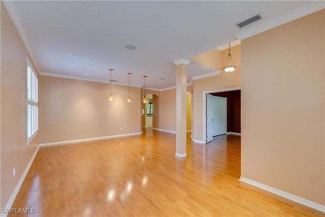 empty room with visible vents, light wood-type flooring, crown molding, and baseboards