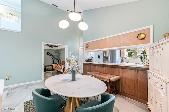 dining space with ceiling fan and a towering ceiling