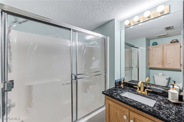 full bathroom featuring vanity, a textured ceiling, toilet, and bath / shower combo with glass door