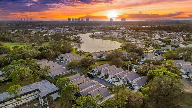 aerial view at dusk featuring a water view