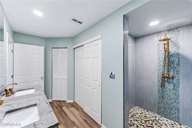 bathroom featuring hardwood / wood-style floors, vanity, and tiled shower