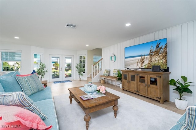 living room featuring french doors, light hardwood / wood-style flooring, and wooden walls