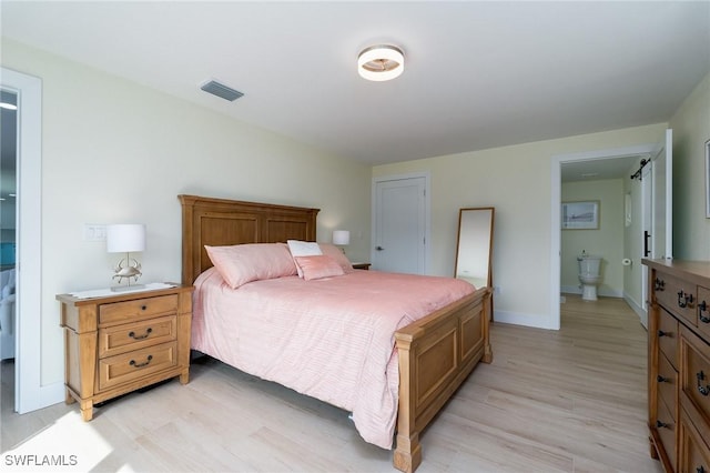 bedroom featuring connected bathroom and light hardwood / wood-style flooring