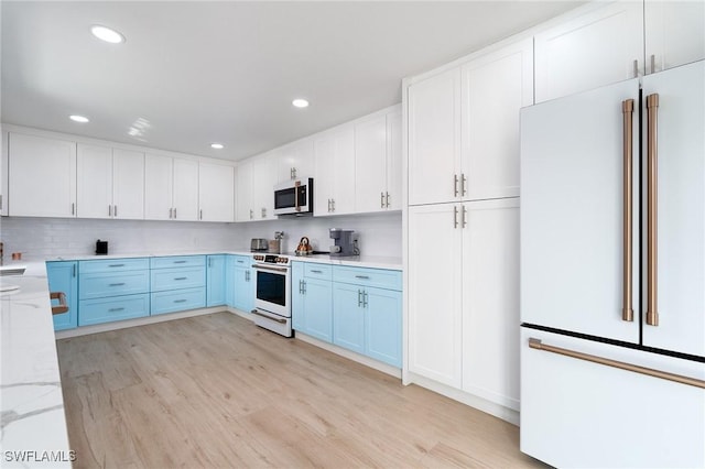 kitchen featuring light stone countertops, backsplash, white appliances, white cabinets, and light wood-type flooring