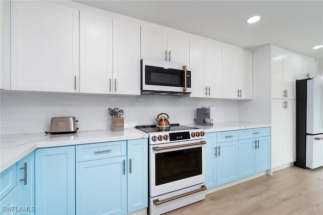 kitchen featuring white cabinetry, decorative backsplash, light stone countertops, and white appliances