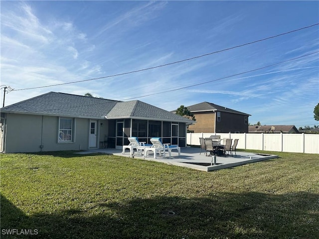 back of property with a sunroom, a patio, and a lawn