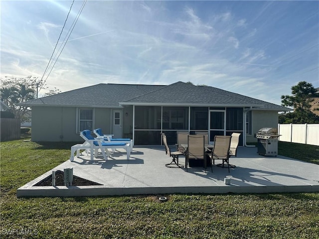 rear view of house featuring a sunroom, a yard, and a patio