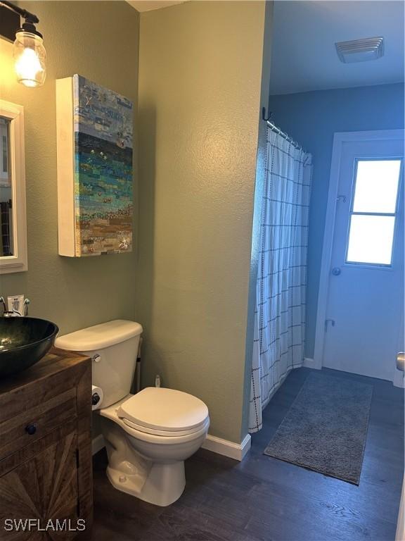 bathroom with hardwood / wood-style flooring, vanity, curtained shower, and toilet