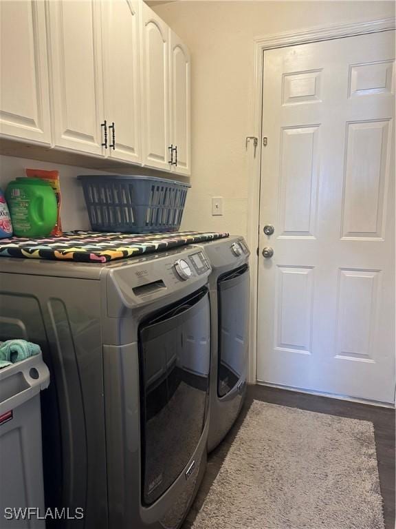 laundry room with washer and clothes dryer, dark hardwood / wood-style floors, and cabinets