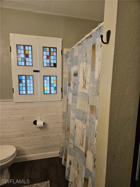 bathroom featuring wood-type flooring, toilet, and wood walls