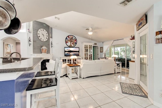 living room featuring ceiling fan, light tile patterned flooring, and vaulted ceiling