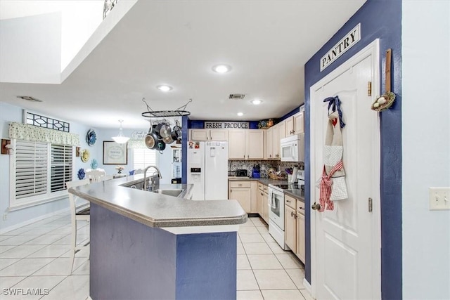 kitchen featuring a kitchen bar, tasteful backsplash, white appliances, sink, and a center island with sink