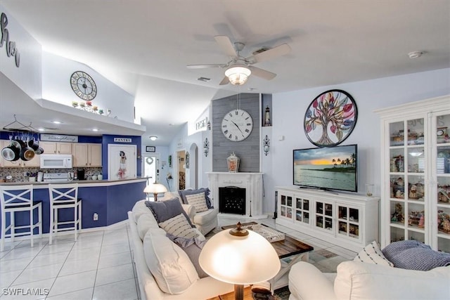 living room with ceiling fan, light tile patterned flooring, and lofted ceiling