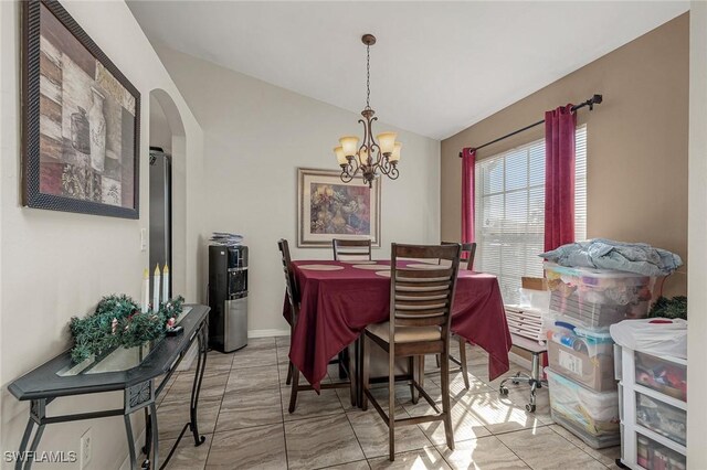 dining area featuring arched walkways, lofted ceiling, and an inviting chandelier