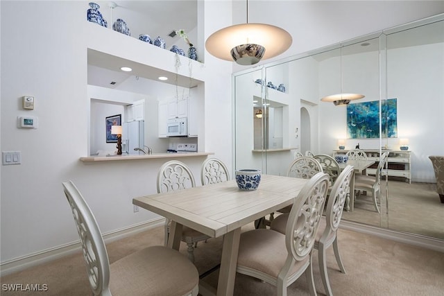 dining space with light colored carpet and a high ceiling