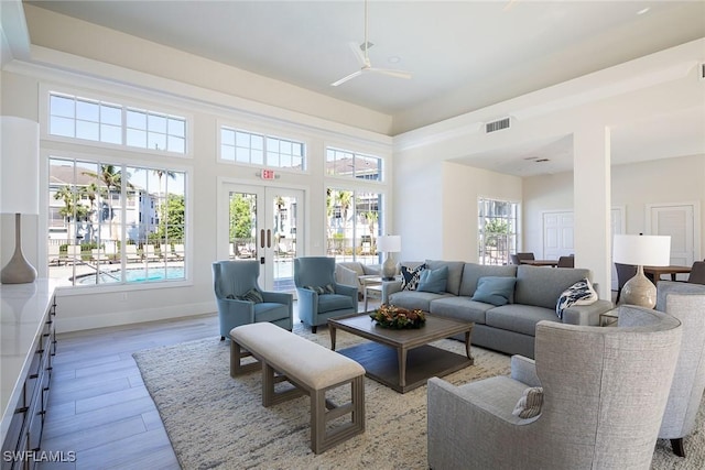 living room featuring french doors, light wood-type flooring, and ceiling fan