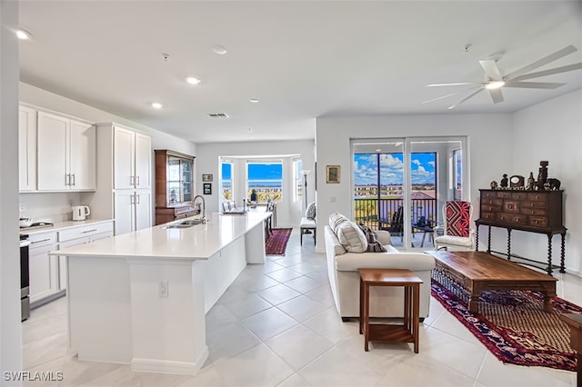 kitchen featuring ceiling fan, white cabinetry, a kitchen island with sink, and sink