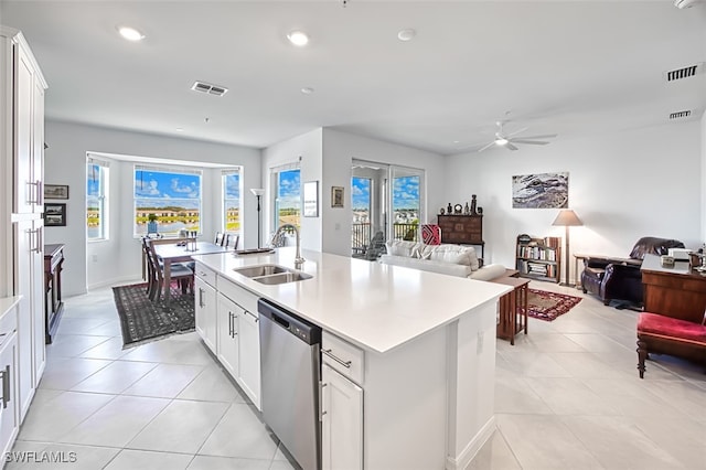 kitchen with stainless steel dishwasher, ceiling fan, sink, a center island with sink, and white cabinetry