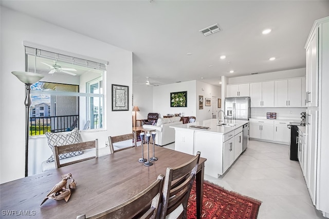 kitchen featuring stainless steel appliances, sink, white cabinets, an island with sink, and light tile patterned flooring