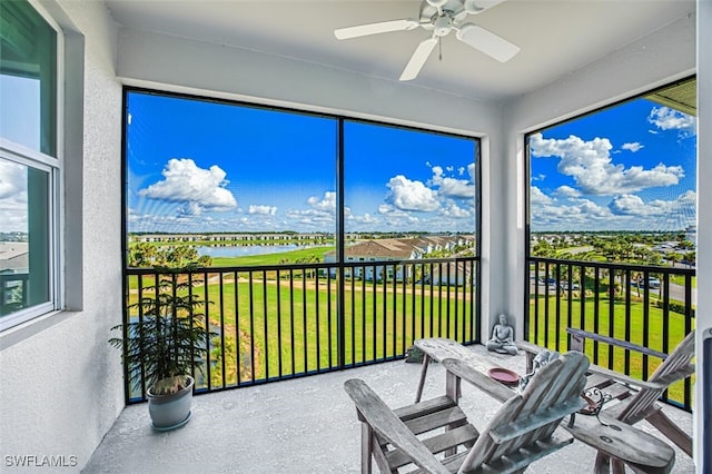 sunroom / solarium featuring a healthy amount of sunlight, ceiling fan, and a water view