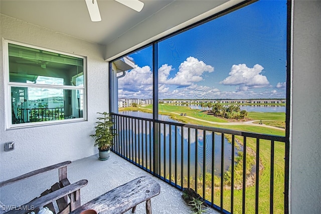 sunroom with ceiling fan and a water view