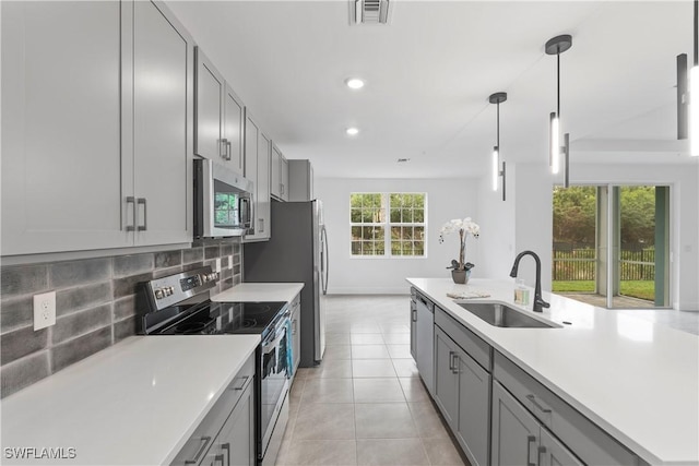 kitchen featuring gray cabinetry, backsplash, sink, hanging light fixtures, and stainless steel appliances