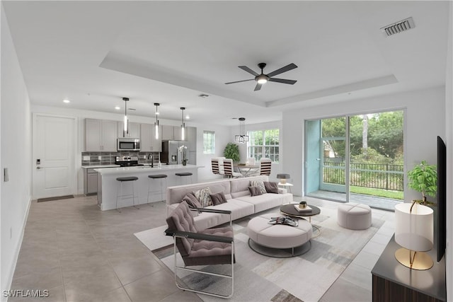 living area featuring light tile patterned floors, ceiling fan, recessed lighting, visible vents, and a raised ceiling